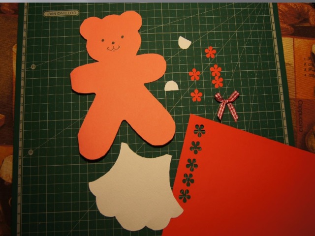 Прорисовываем мордочку медвежонка. Вырезаем из акварельной бумаги по шаблону платье и ушки, подготавливаем детали для украшения.