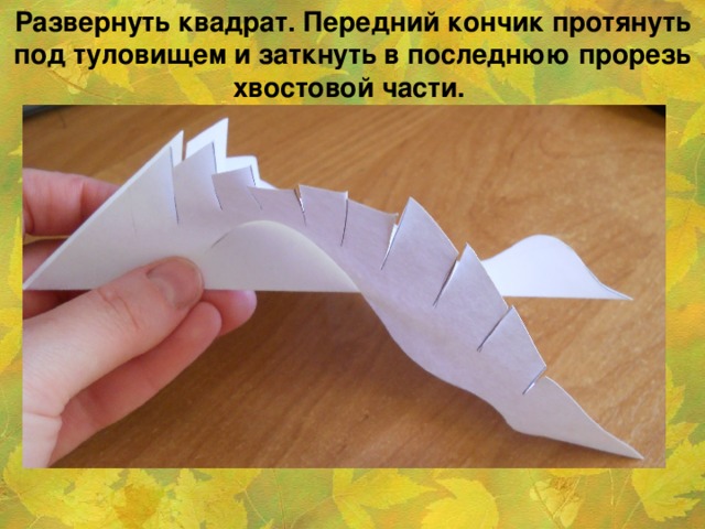 Развернуть квадрат. Передний кончик протянуть под туловищем и заткнуть в последнюю прорезь хвостовой части.